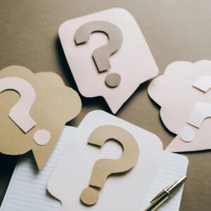 Artistic paper question marks on an open notebook with a pen, symbolizing curiosity and creativity.